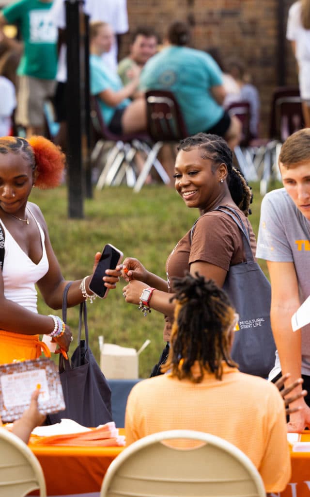 group of students smiling at table during outdoor event